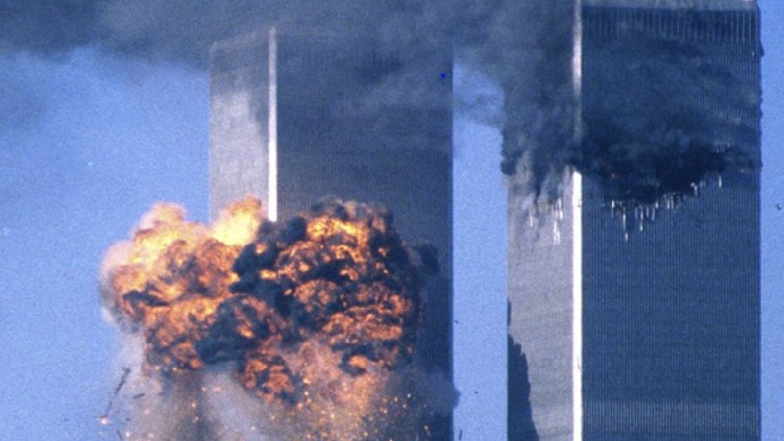 Explosão na Torre Sul do World Trade Center após o impacto do segundo avião, enquanto a Torre Norte aparece coberta por fumaça.